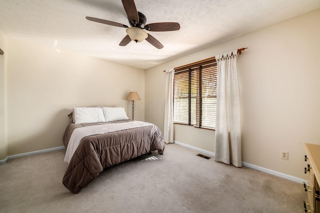 bedroom with light carpet, ceiling fan, and a textured ceiling