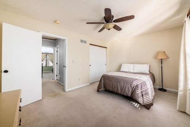 carpeted bedroom with a textured ceiling, a closet, and ceiling fan