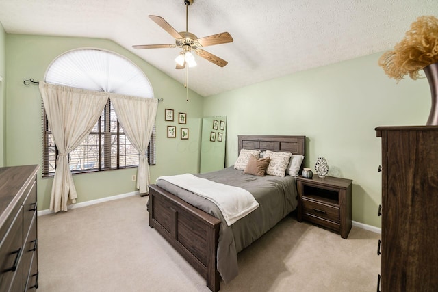 bedroom featuring ceiling fan, vaulted ceiling, light carpet, and a textured ceiling