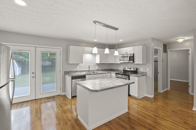 kitchen with pendant lighting, stainless steel appliances, and white cabinets