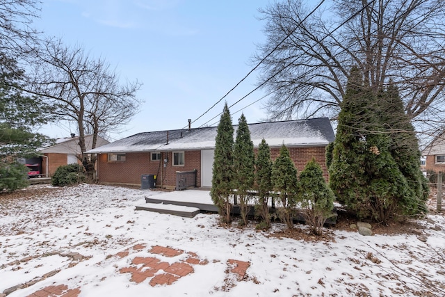 snow covered rear of property featuring a wooden deck and central AC unit