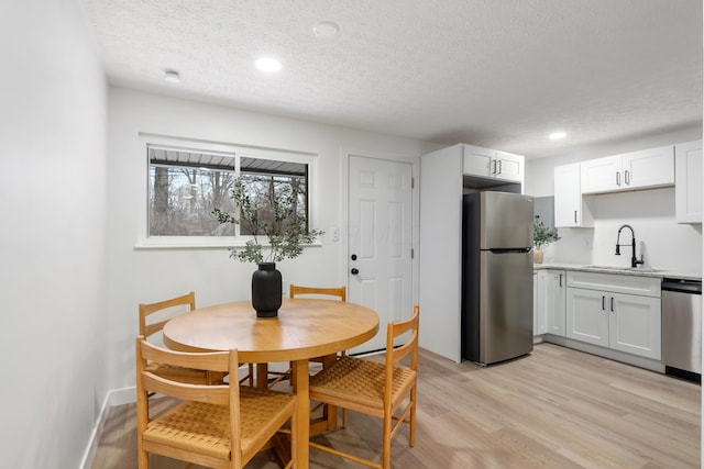 dining space featuring sink, a textured ceiling, and light wood-type flooring