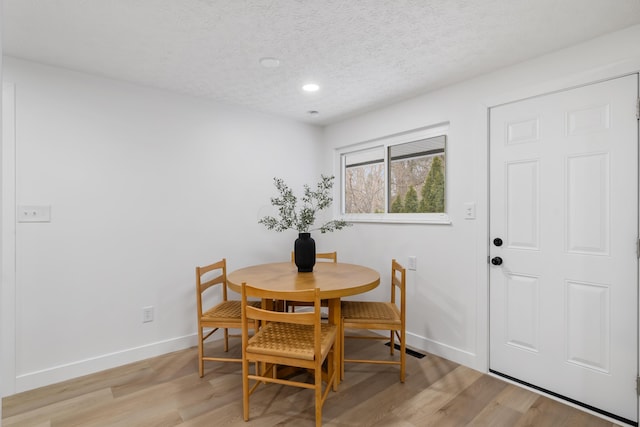 dining area featuring a textured ceiling and light hardwood / wood-style floors