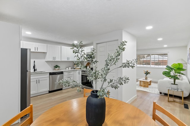 dining room with sink, light hardwood / wood-style flooring, and a textured ceiling