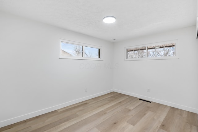 spare room with plenty of natural light and light hardwood / wood-style floors