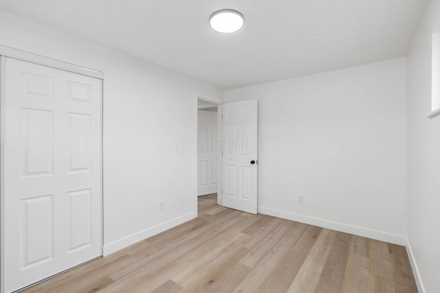 unfurnished bedroom with light hardwood / wood-style floors and a closet