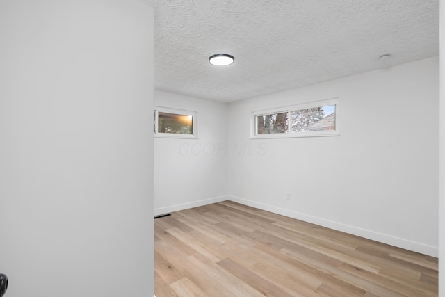 empty room with light hardwood / wood-style flooring and a textured ceiling