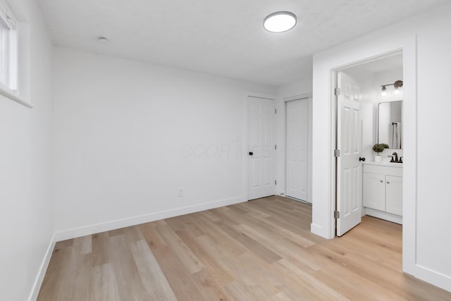 unfurnished bedroom with light wood-type flooring and ensuite bath