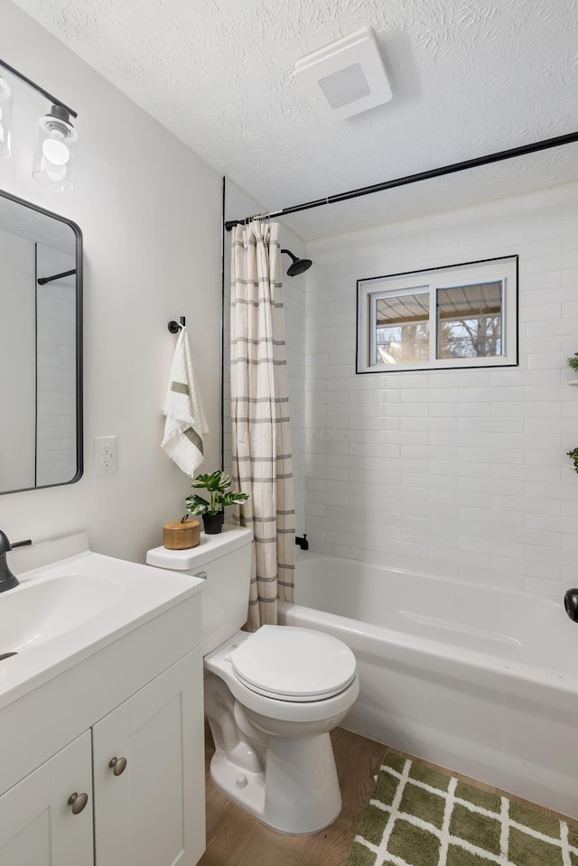 full bathroom with wood-type flooring, vanity, shower / tub combo, toilet, and a textured ceiling