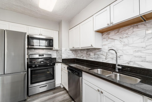 kitchen featuring white cabinetry, sink, dark stone counters, and appliances with stainless steel finishes