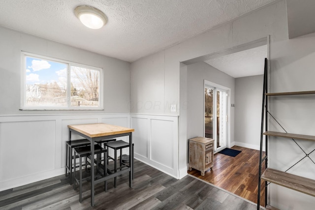 dining space with a textured ceiling and dark hardwood / wood-style flooring