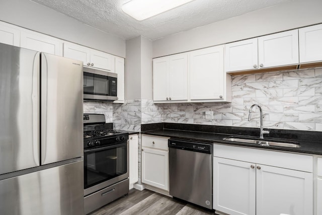 kitchen featuring sink, appliances with stainless steel finishes, white cabinetry, dark hardwood / wood-style floors, and tasteful backsplash