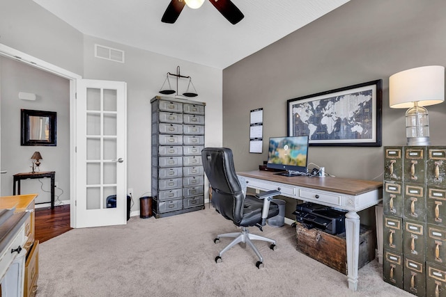 carpeted home office featuring french doors and ceiling fan