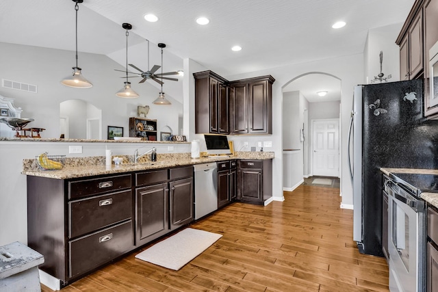 kitchen with appliances with stainless steel finishes, dark brown cabinets, pendant lighting, and kitchen peninsula