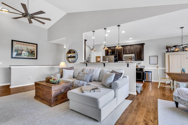 living room with lofted ceiling, ceiling fan, and light wood-type flooring