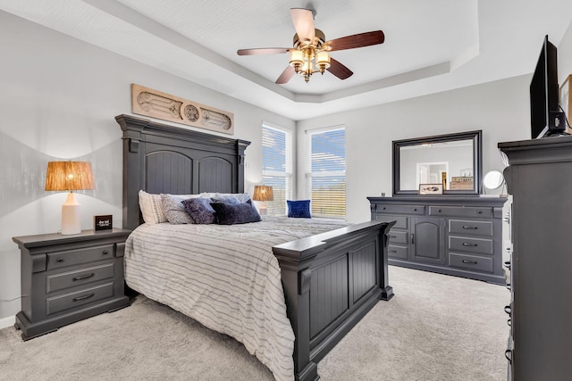 carpeted bedroom featuring a raised ceiling and ceiling fan