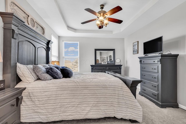 carpeted bedroom featuring ceiling fan and a raised ceiling