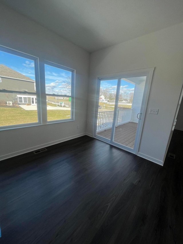 unfurnished room with dark wood-style floors, baseboards, and visible vents