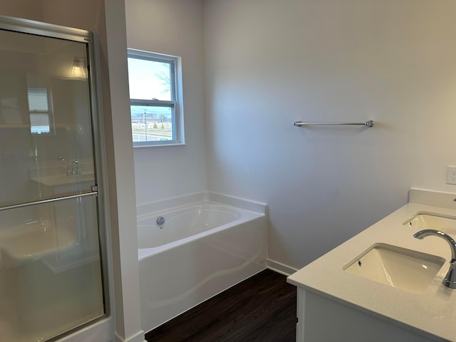 full bath featuring a shower stall, double vanity, a sink, and a garden tub