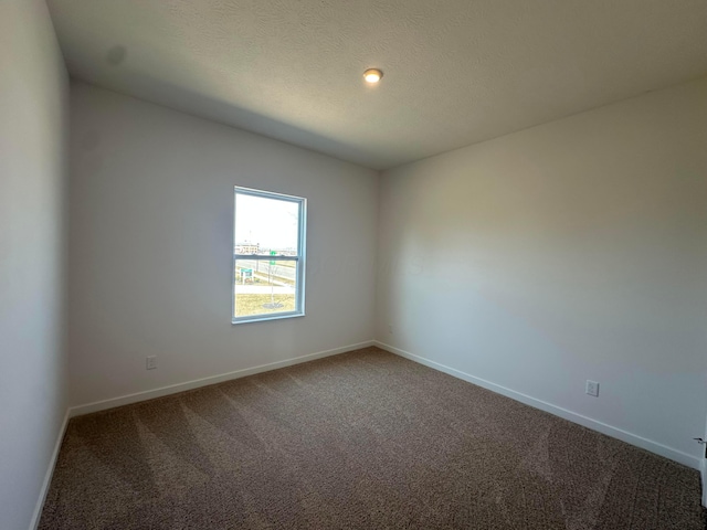 carpeted spare room with baseboards and a textured ceiling