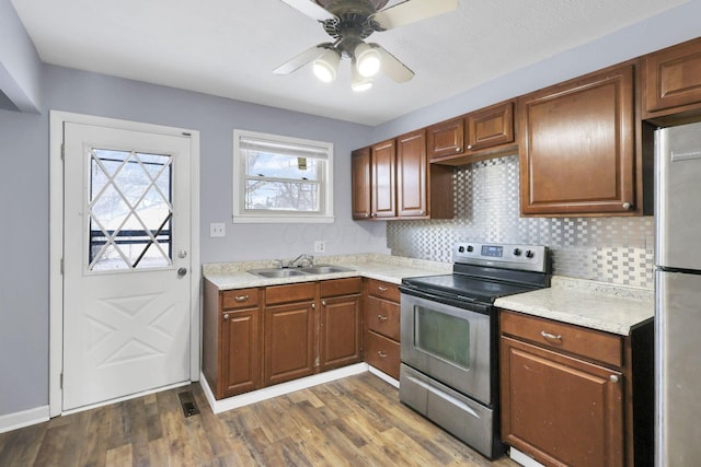 kitchen with sink, ceiling fan, backsplash, stainless steel appliances, and dark hardwood / wood-style floors