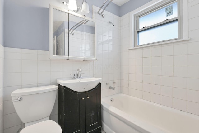 full bathroom with vanity, toilet, tiled shower / bath combo, and tile walls