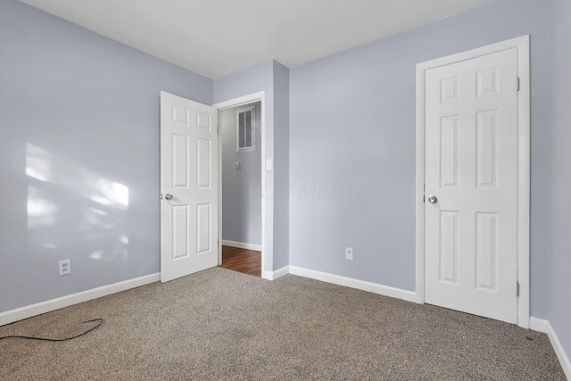 unfurnished bedroom with dark colored carpet