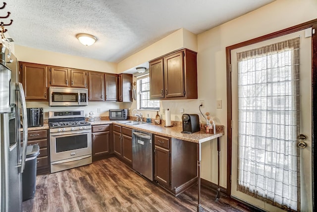 kitchen featuring sink, stainless steel appliances, dark hardwood / wood-style floors, and a textured ceiling