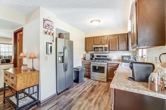 kitchen with stainless steel appliances, dark hardwood / wood-style floors, sink, and a textured ceiling