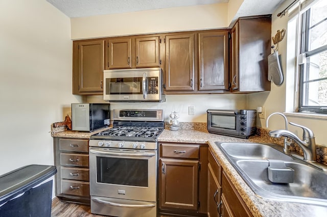 kitchen with stainless steel appliances, sink, wood-type flooring, and a textured ceiling