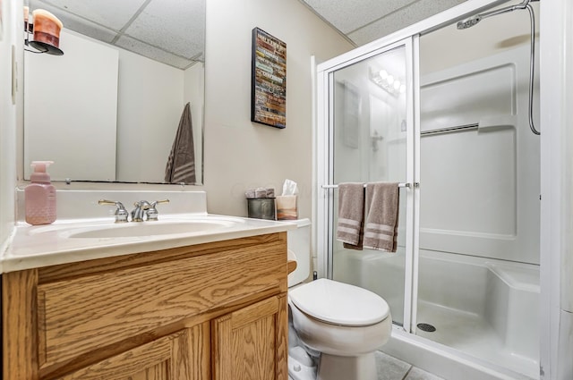 bathroom featuring a paneled ceiling, vanity, toilet, and a shower with shower door