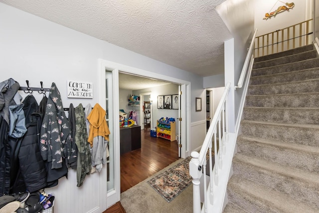 stairway with hardwood / wood-style flooring and a textured ceiling