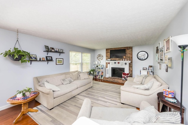 living room featuring a brick fireplace, a textured ceiling, and light wood-type flooring