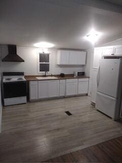 kitchen featuring white cabinetry, white appliances, sink, and wall chimney range hood