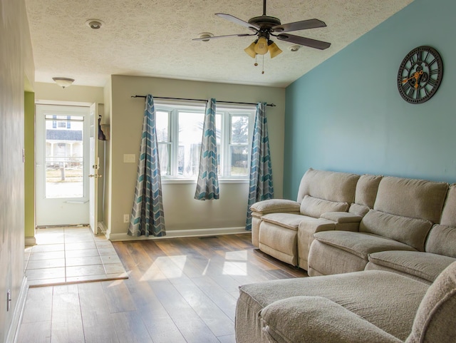 living room featuring a ceiling fan, a wealth of natural light, light wood-style flooring, and a textured ceiling