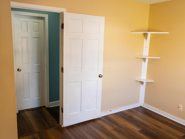 unfurnished bedroom with baseboards and dark wood finished floors