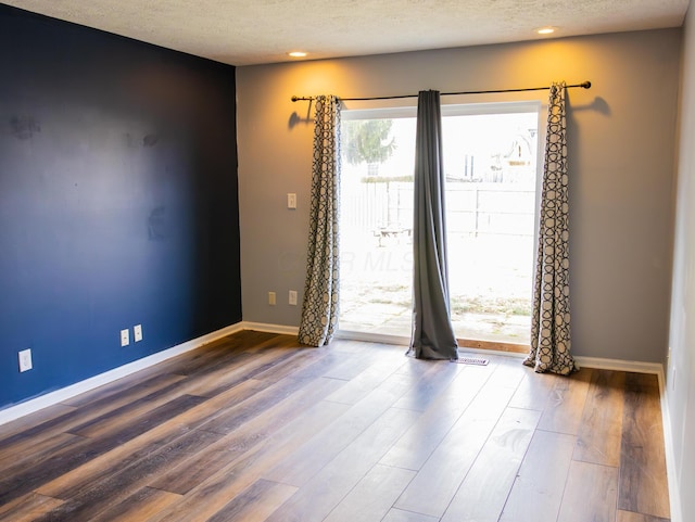 unfurnished room featuring recessed lighting, a textured ceiling, baseboards, and wood finished floors