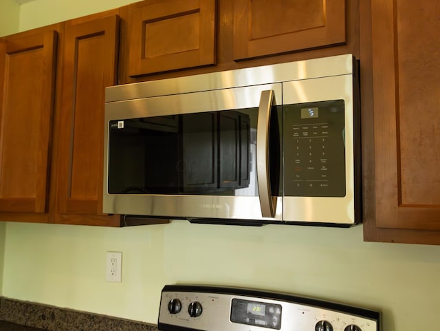 interior details with brown cabinets, dark countertops, stainless steel microwave, and range