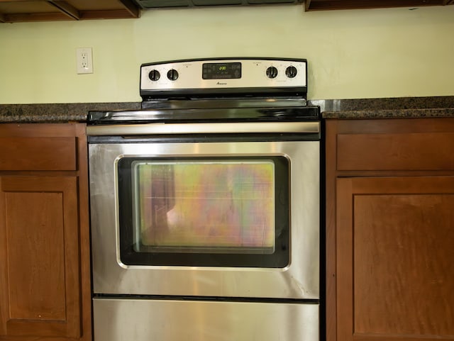 kitchen featuring dark stone countertops, brown cabinets, and stainless steel range with electric cooktop