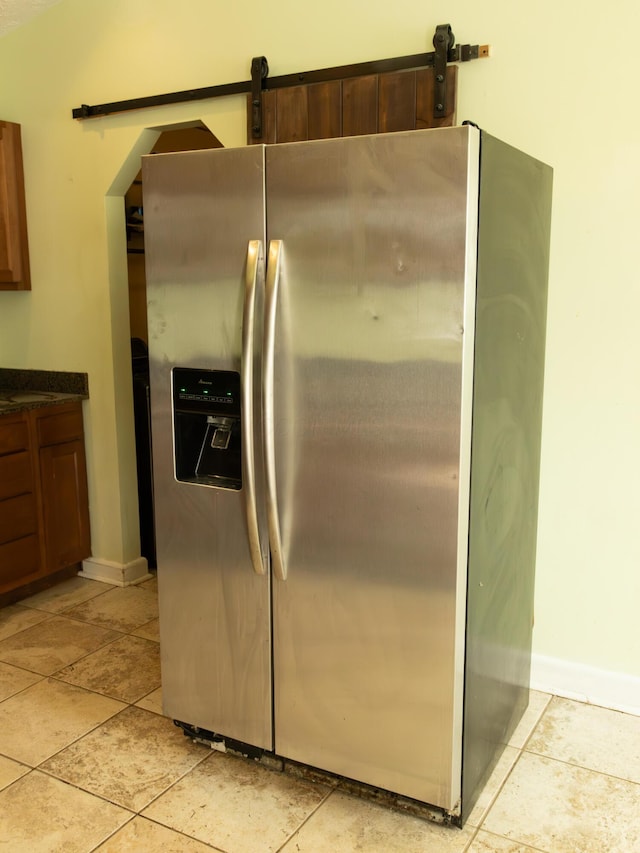 kitchen featuring baseboards, dark countertops, and stainless steel fridge with ice dispenser