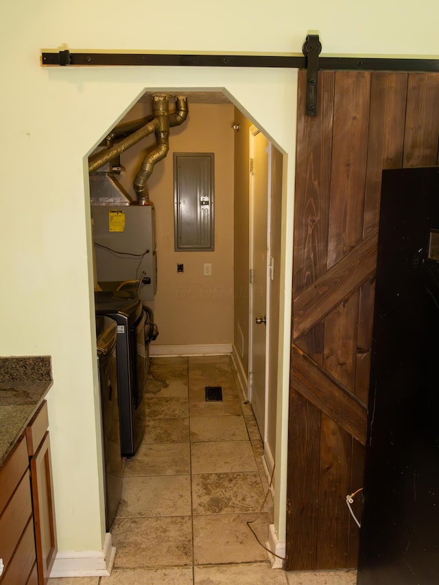 clothes washing area with electric panel, washer and clothes dryer, baseboards, and a barn door