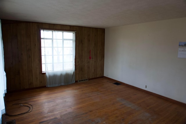 unfurnished room featuring visible vents, baseboards, and wood finished floors