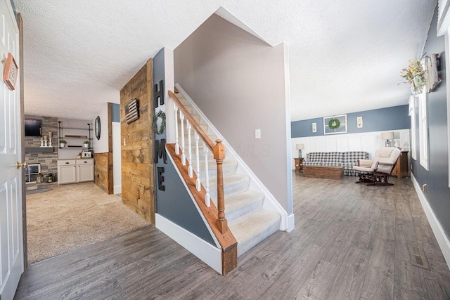 stairway with hardwood / wood-style floors and a textured ceiling