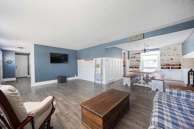 living room with dark hardwood / wood-style flooring, a notable chandelier, built in features, and a textured ceiling