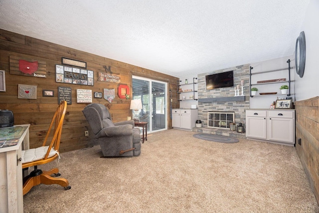 carpeted living room featuring a stone fireplace, a textured ceiling, and wood walls