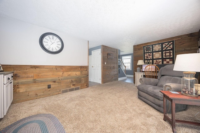 carpeted living room featuring a textured ceiling and wood walls