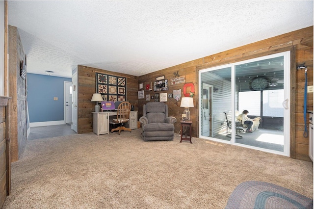 sitting room featuring carpet, a textured ceiling, and wooden walls