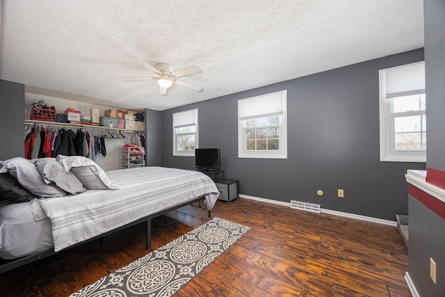 bedroom with ceiling fan, dark hardwood / wood-style flooring, a closet, and a textured ceiling