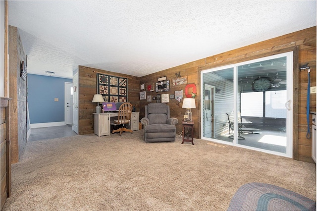 living area featuring carpet floors, wooden walls, and a textured ceiling