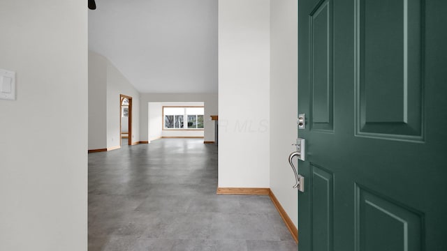 foyer featuring lofted ceiling and concrete floors